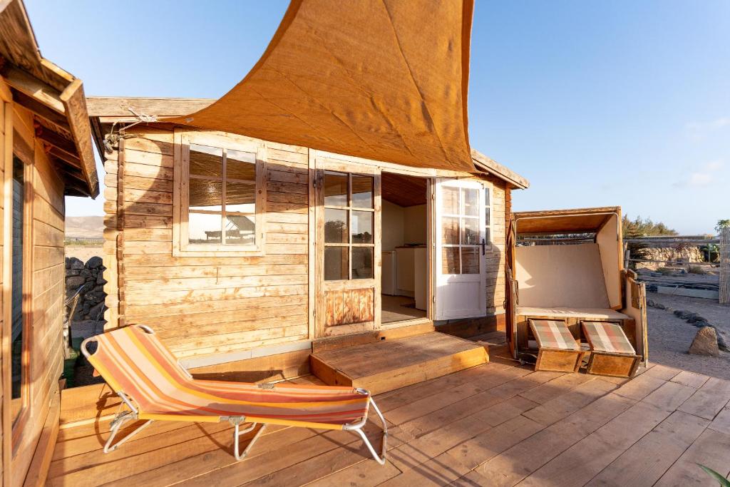 a house with a deck and two chairs on it at Alaia Tiny House between volcanoes and beach breaks in El Cotillo