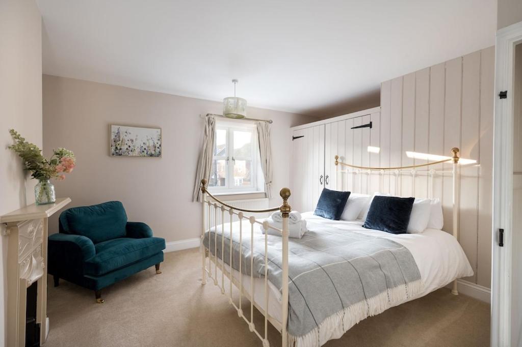 a bedroom with a bed and a blue chair at Rose Cottage, Snettisham, Norfolk in Snettisham