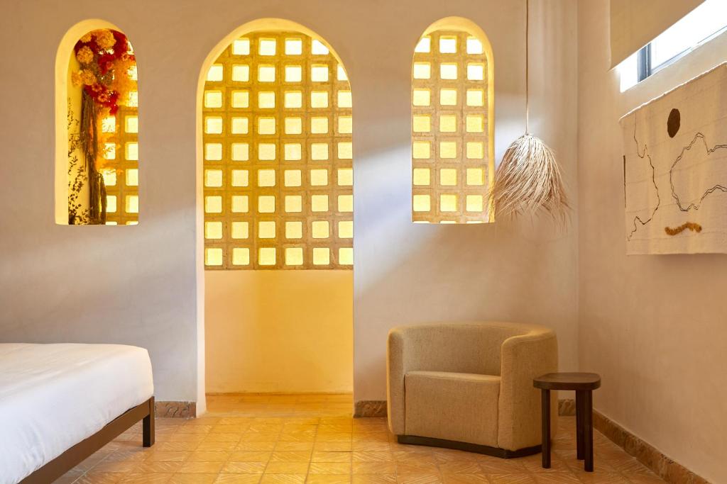 een slaapkamer met een bed, een stoel en ramen bij DUNA by DW in San Juan