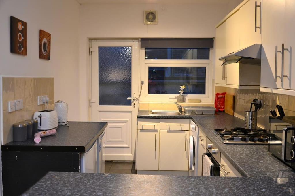 a kitchen with white cabinets and a black counter top at Cozy home near city, sleeps 5, Free Parking, WIFI in Liverpool