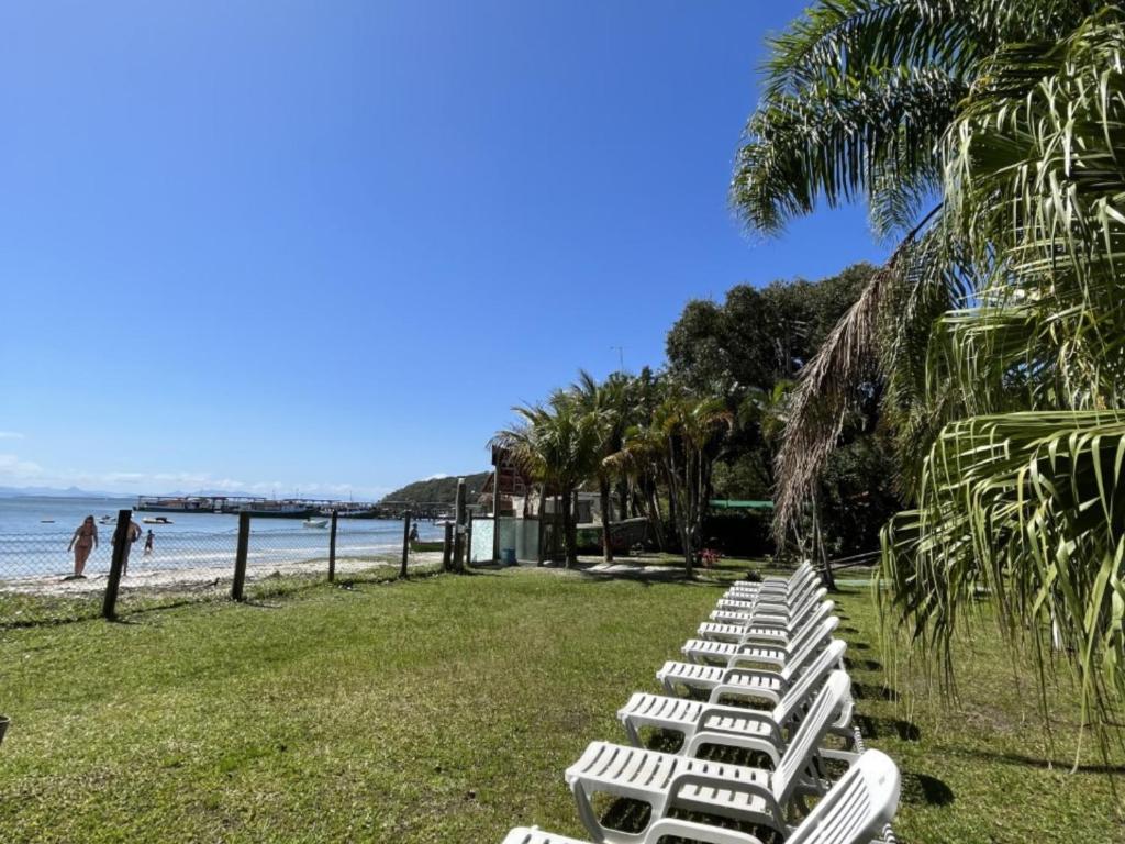 a row of white lounge chairs on the beach at A Ilha Verde Hotel Pousada na Praia in Ilha do Mel