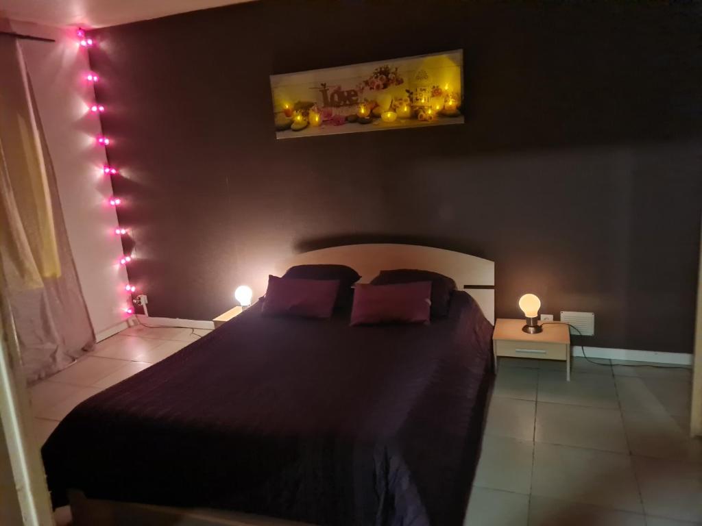 a bedroom with a bed with lights on the wall at Appartement chaleureux au pied du tramway et à 10 mn de Valenciennes. in Denain