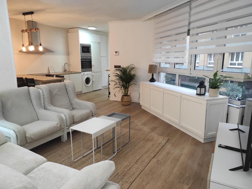a living room with white furniture and a kitchen at Centro playa, apartamento con garaje in Gijón