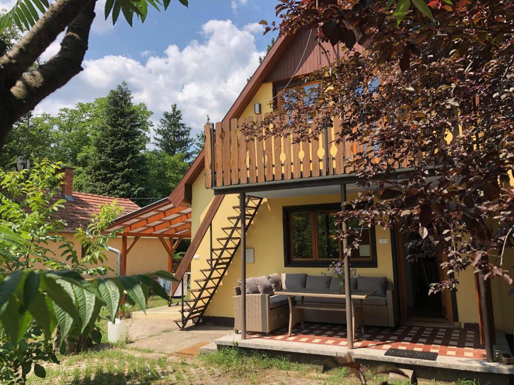 Kunfehértó的住宿－Forest-side home by recreational lake，带阳台和沙发的门廊房屋