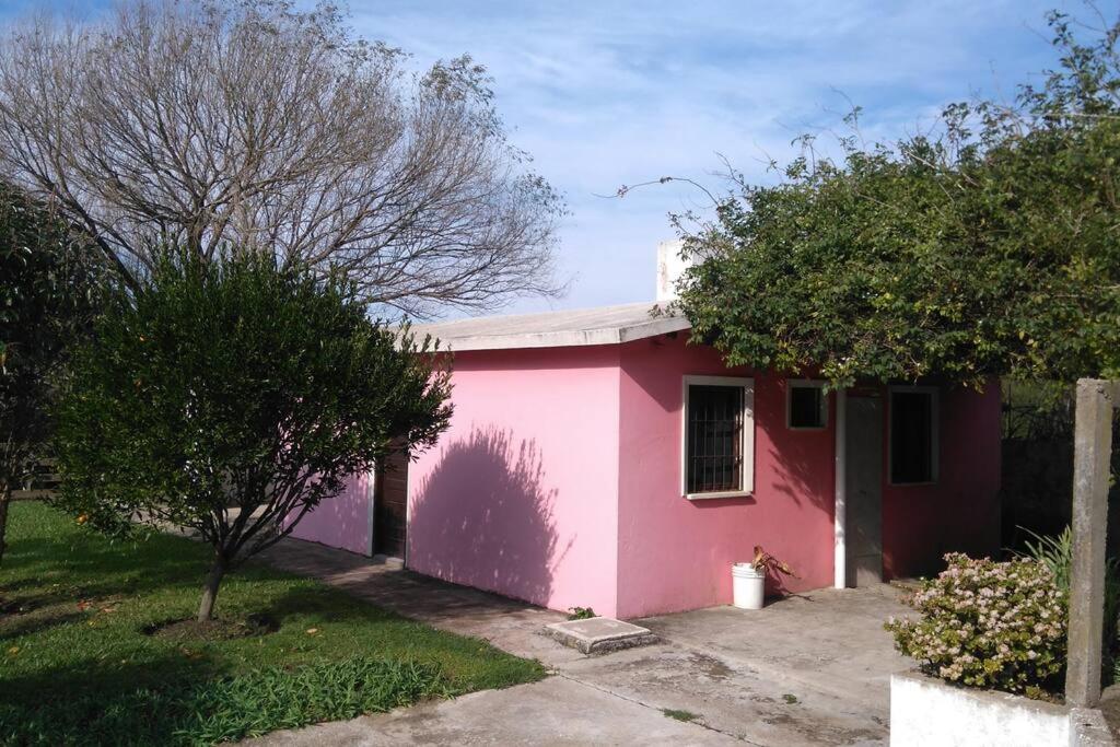 ein rosafarbenes Haus mit Bäumen davor in der Unterkunft La Rosadita, un escape tranquilo en La Pedrera. in La Pedrera