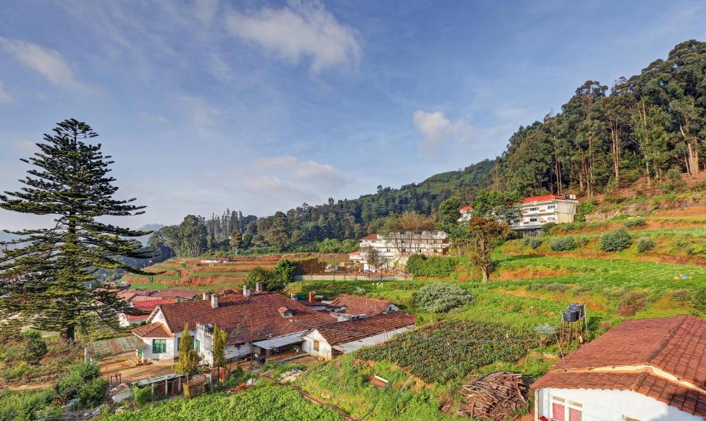 a village on the side of a hill with houses at Itsy By Treebo - Rain Forest in Ooty