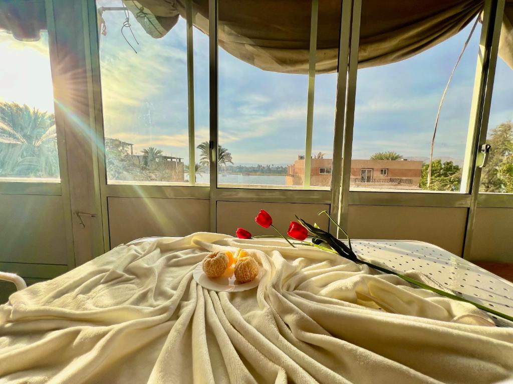 - un lit avec des fleurs et une fenêtre dans l'établissement Nile Horizon apartments, à Jazīrat al ‘Awwāmīyah