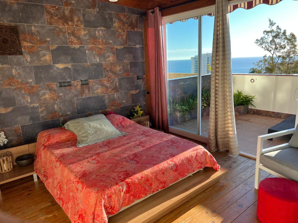 ein Schlafzimmer mit einem Bett und einem großen Fenster in der Unterkunft Duplex de lujo en la playa , jacuzzy, piscina, chimenea y padel in Benalmádena