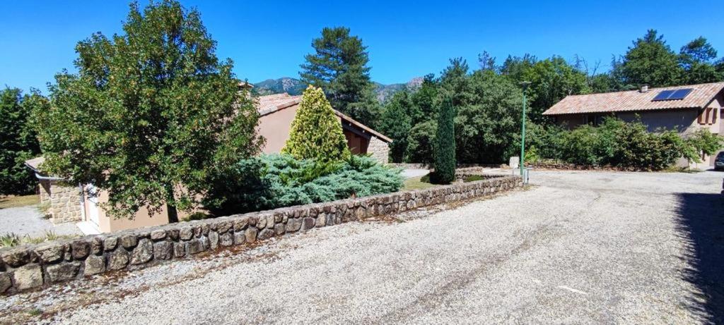 an empty road in front of a house with a stone wall at La Peyreyre in Jaujac