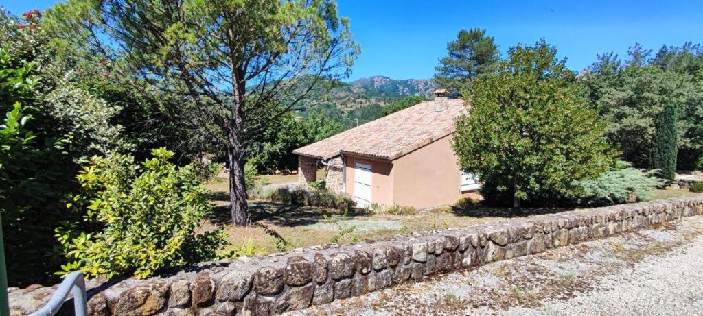 a small house with a stone wall next to a building at La Peyreyre in Jaujac