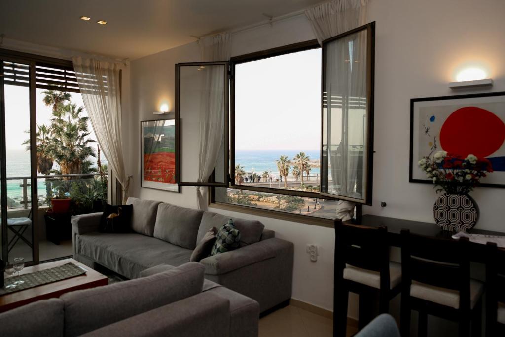 een woonkamer met een bank en grote ramen bij Sea View Apartment Prime Location On The Beach in Tel Aviv