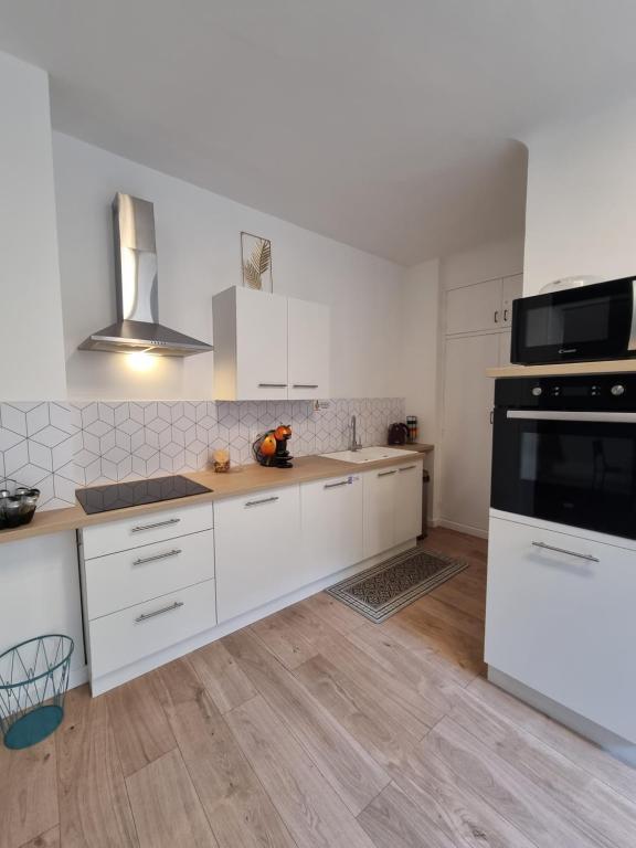 een keuken met witte kasten en een zwart apparaat bij Mon Petit Patio - 4 chambres in Fourques