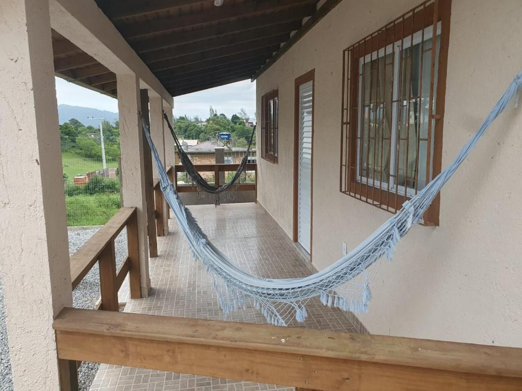 a porch with a hammock on the side of a building at Casa proxima a Praia do Rosa e Barra de Ibiraquera 2 quartos com ar condicionado in Imbituba