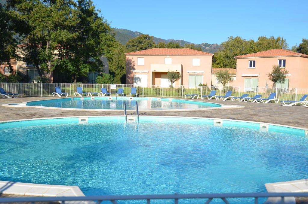 a large swimming pool with chairs and a house in the background at Villa Fior 50 in Santa-Maria-Poggio