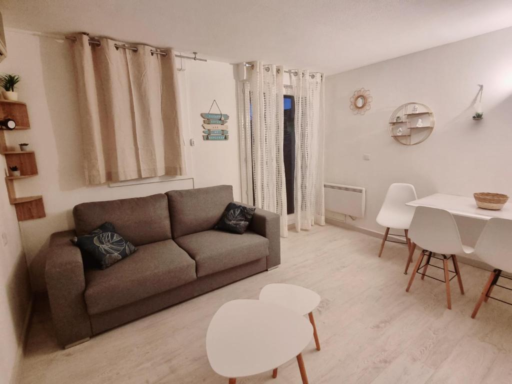a living room with a couch and a table at 100 m de la plage - Les Cigales de Mer - Studio Cabine - Parking in Le Grau-du-Roi