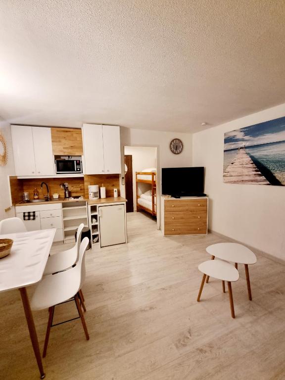 a kitchen with white cabinets and a table and chairs at 100 m de la plage - Les Cigales de Mer - Studio Cabine - Parking in Le Grau-du-Roi