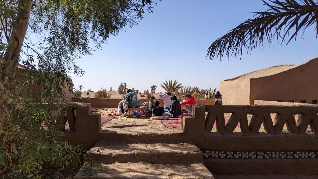 a group of people sitting on the ground near a building at Chez Madani in Mhamid