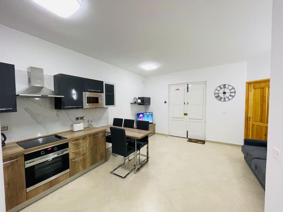 een keuken met een tafel en stoelen in een kamer bij New, Modern Ground Floor Apartment with Pool in Għajnsielem