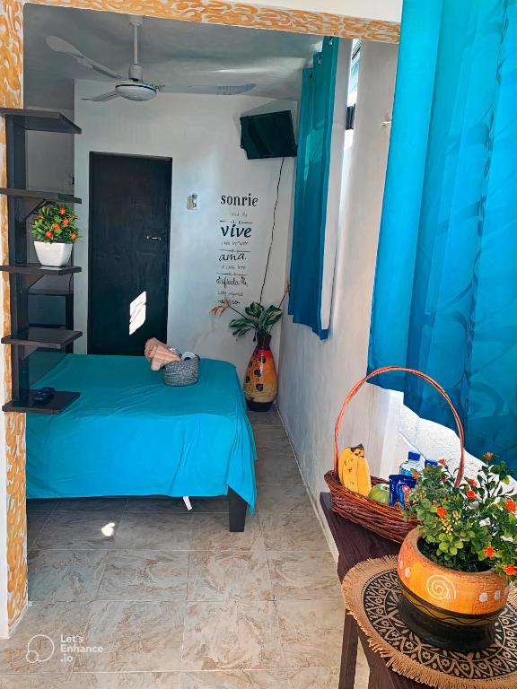 a bedroom with a blue bed and a table with a basket at Cuartos kukulcan in Valladolid