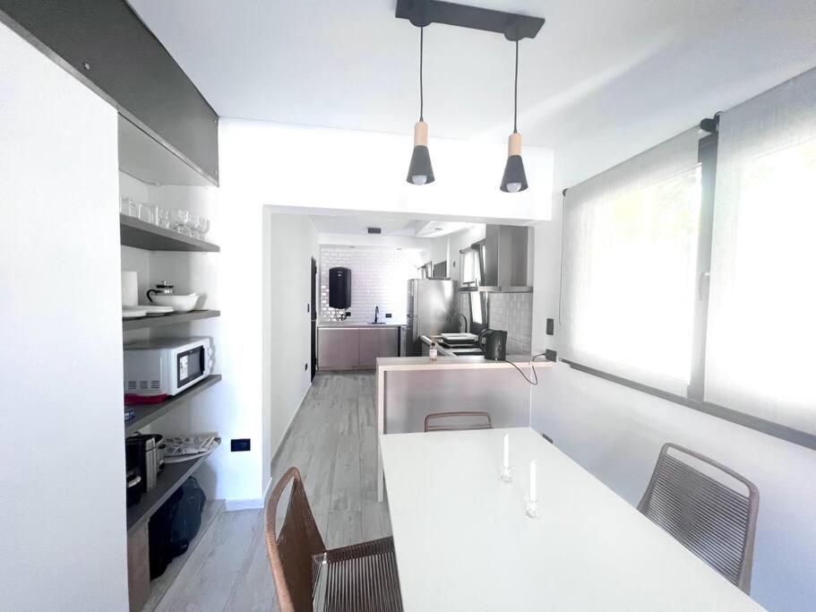 - une cuisine blanche avec un comptoir et des chaises blancs dans l'établissement Beach House Monte Hermoso, à Monte Hermoso