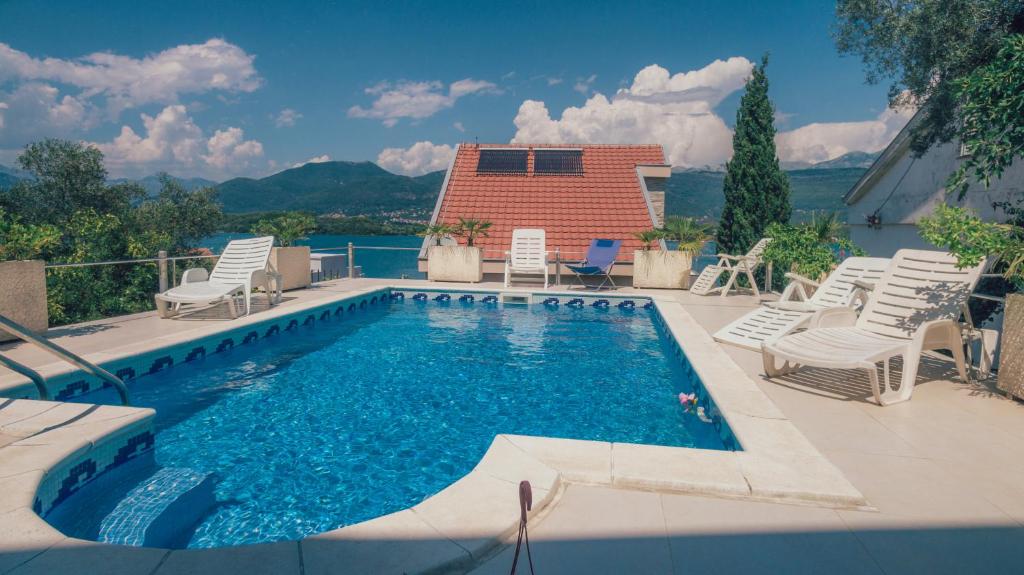 a swimming pool with chairs and a house at Villa Tivat in Tivat