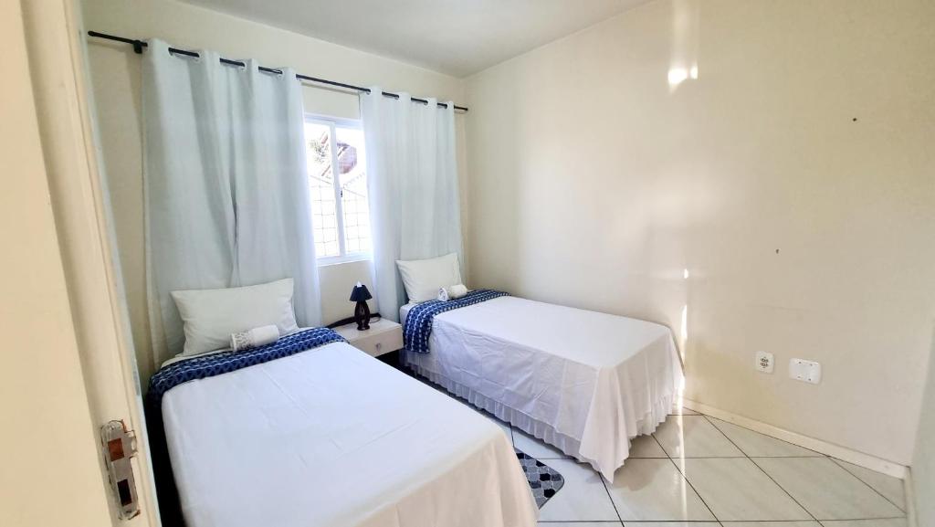 1 dormitorio con 2 camas y ventana en Residencial Cristina's-Apartamentos de 2-3 Quartos equipados com WiFi Garagem-Excelente Localização, en Lages