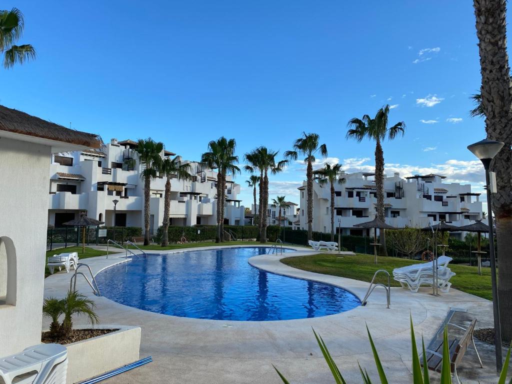 - une piscine bordée de palmiers et de bâtiments dans l'établissement Apartamento Vera Playa, à Vera