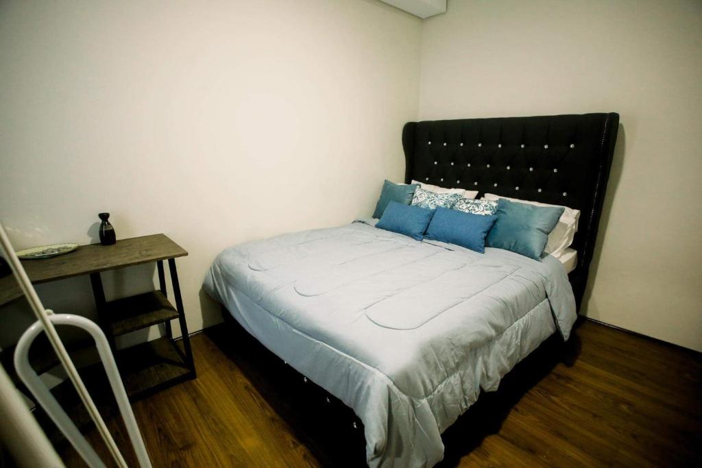 a bedroom with a bed with blue pillows and a table at JHS condotel in Roxas City