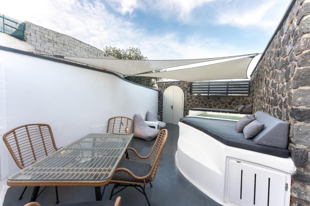 a patio with a table and chairs on a balcony at Sun Naam Home Santorini with heated jacuzzi in Karterados