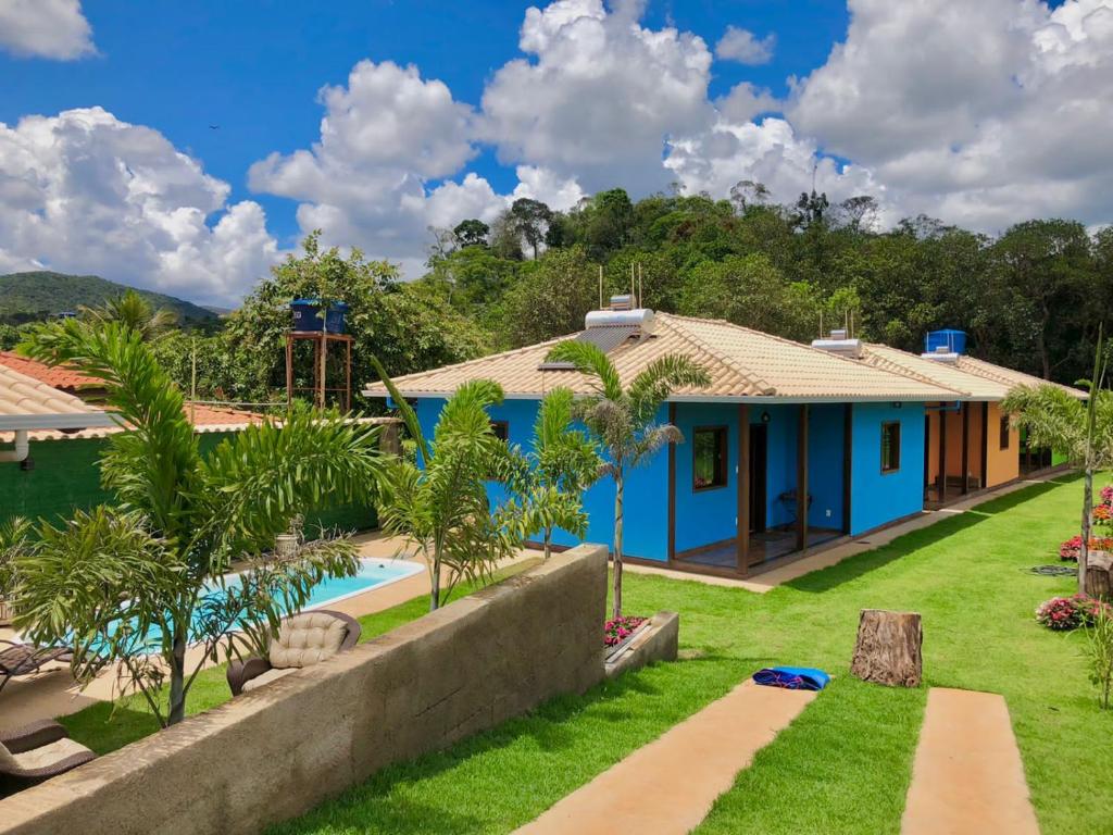 a blue house with a swimming pool and trees at Vila Verde Chalés-Serro in Sêrro