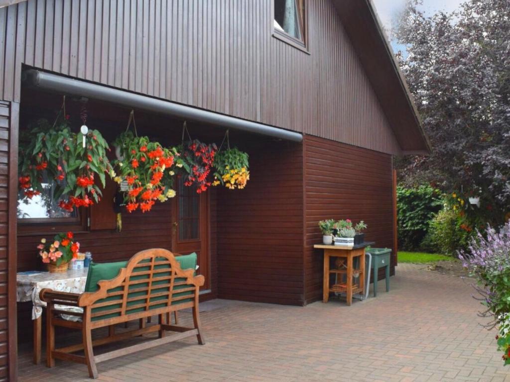eine Terrasse mit einer Bank und Blumen, die von einem Gebäude hängen in der Unterkunft Kranich-Holzferienhaus 'Kleine Auszeit' in Rehden