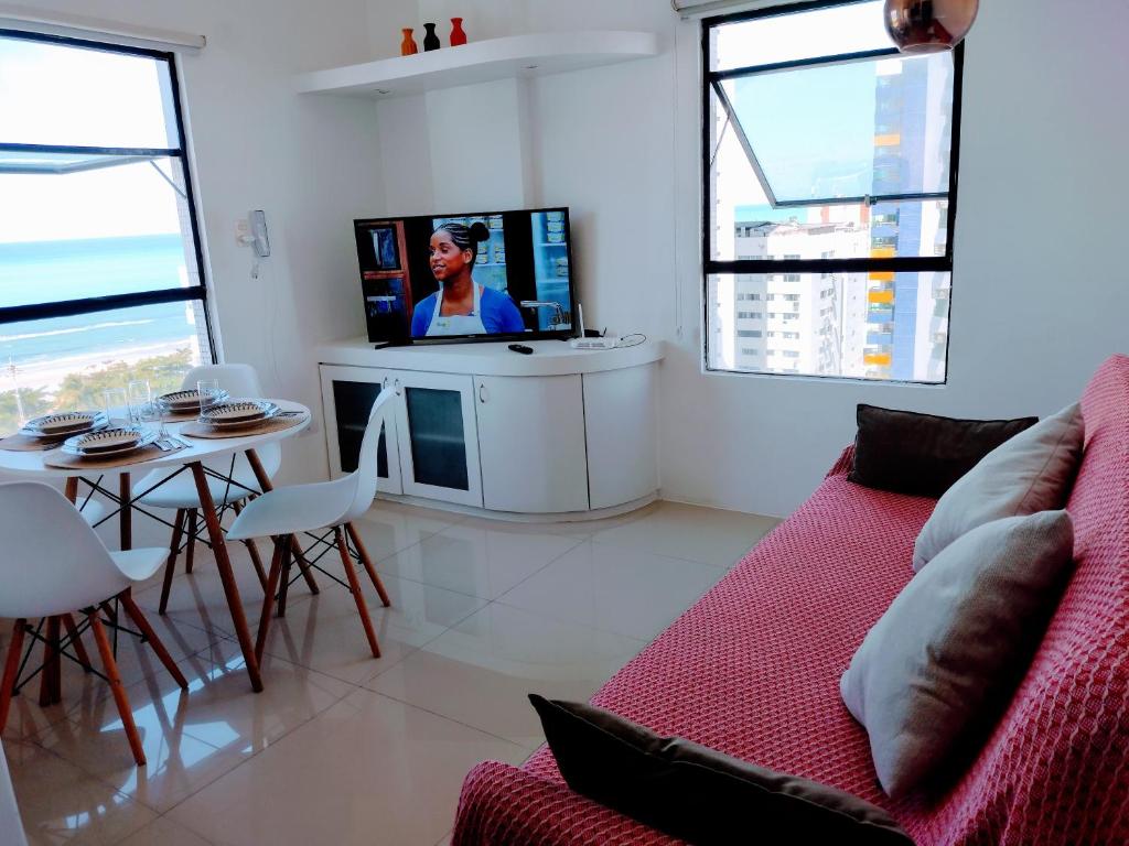 uma sala de estar com um sofá e uma televisão em Apto de frente para o Mar, Piscina na cobertura em Recife