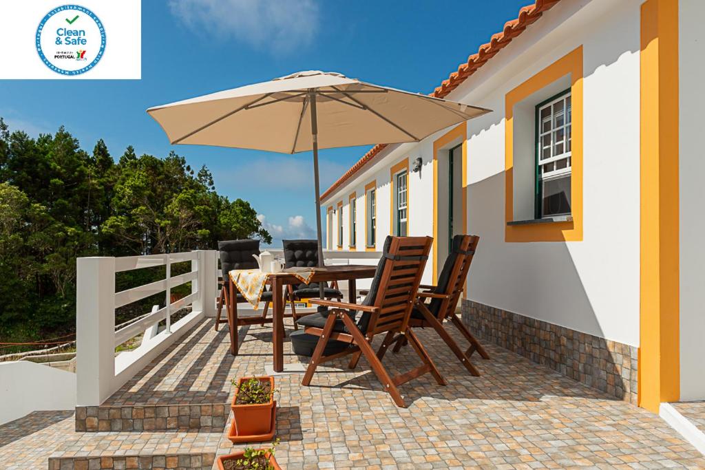 a patio with a table and an umbrella at Casa da Figueirinha in Calheta de Nesquim