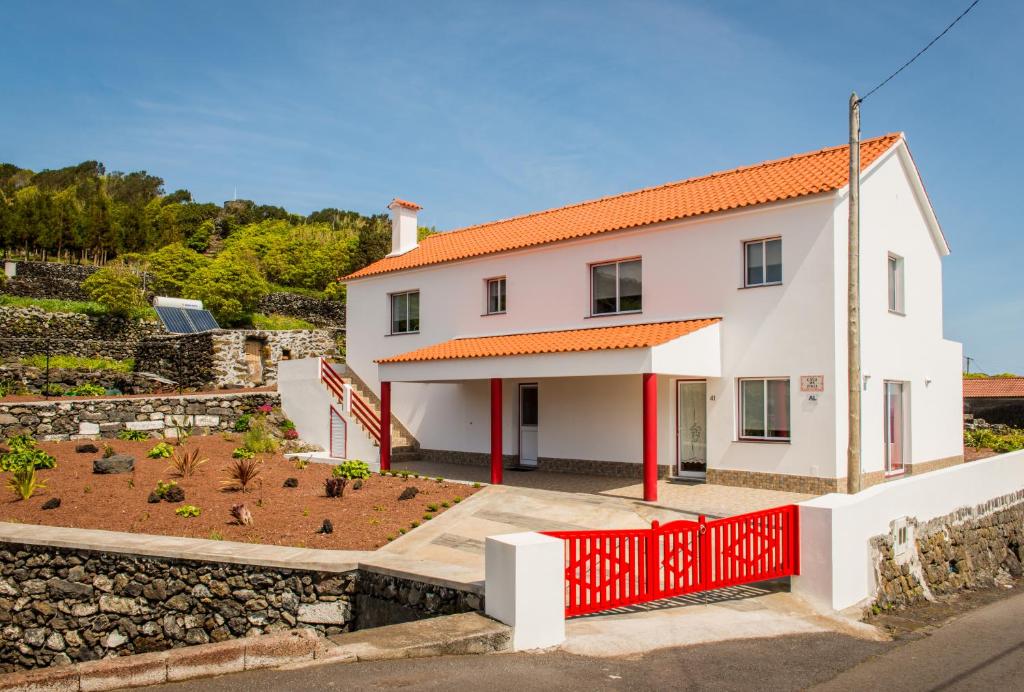 a white house with an orange roof and a red fence at Casa da Vigia in Calheta de Nesquim
