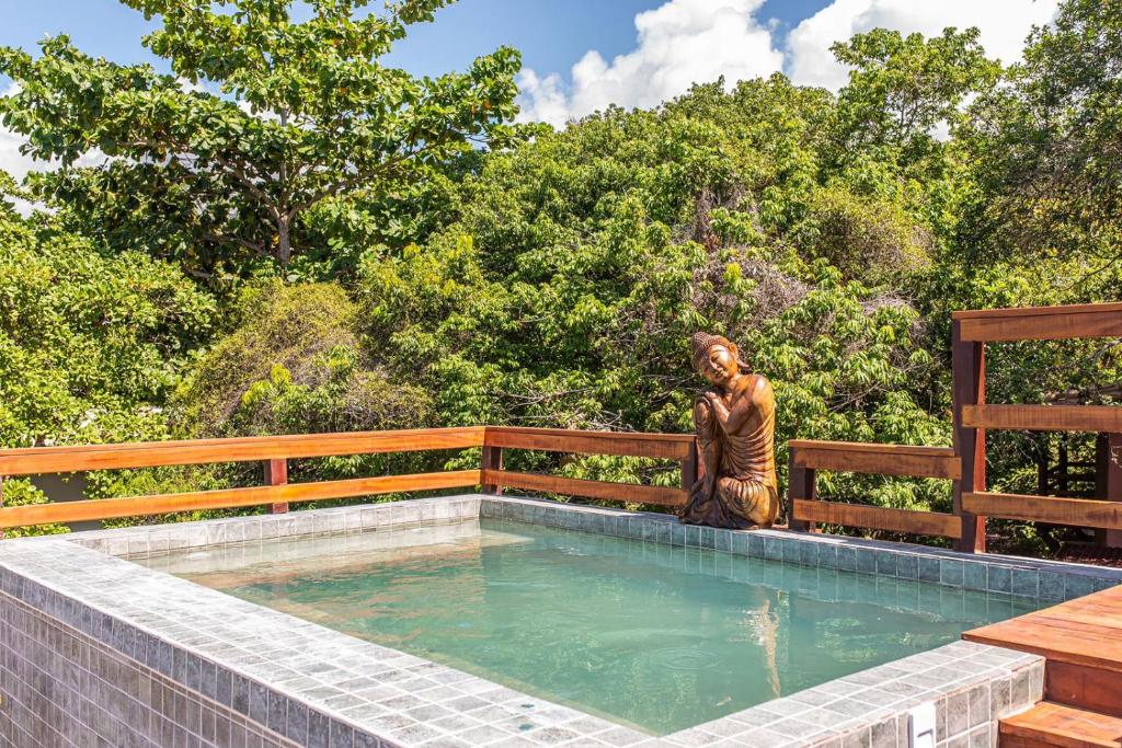 a statue sitting on a fence next to a swimming pool at Canto dos Sonhos Caraíva in Caraíva