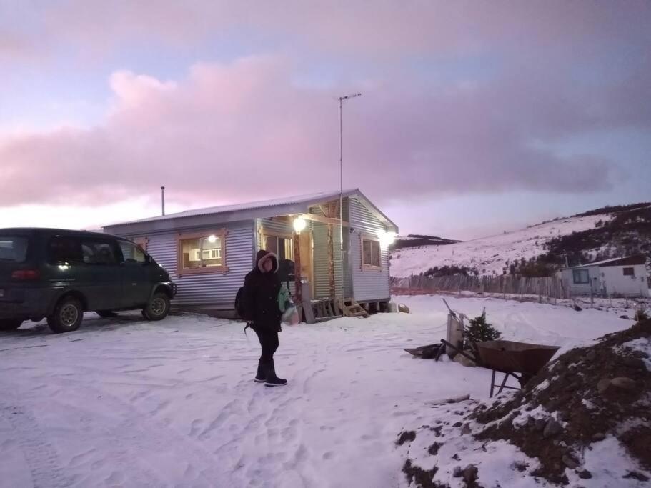 a person standing in the snow in front of a house at Cabañas La Frontera. in Puerto Natales