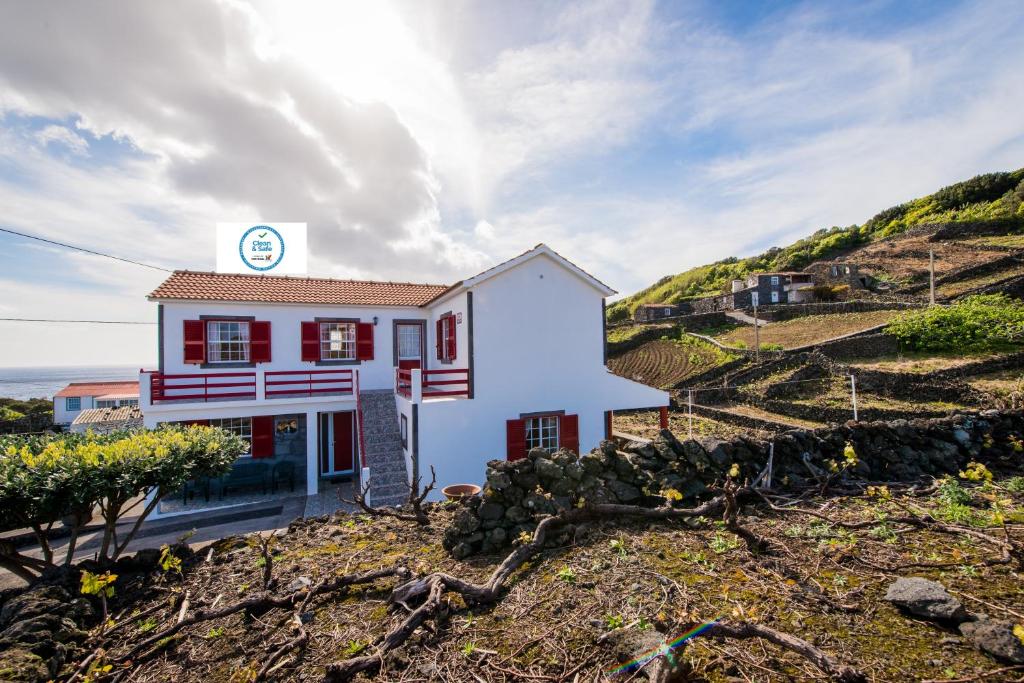 mały biały dom na szczycie wzgórza w obiekcie Adega Pedra do Lagar w mieście Calheta de Nesquim