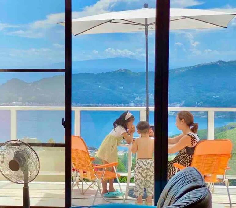 a group of children sitting at a table on a balcony at 雲海オーシャンビュー熱海天空 in Taga
