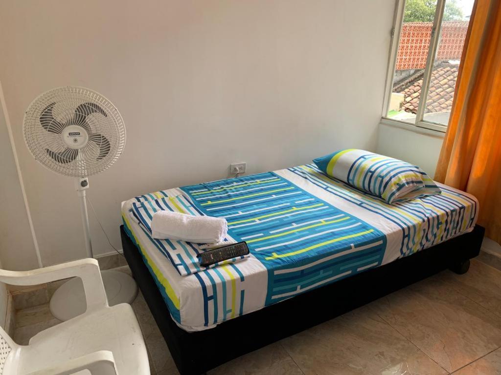 Hospedaje Alférez Real في Jamundí: غرفة نوم بسرير مع مروحة وكرسي