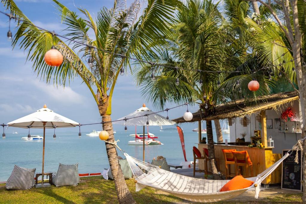 a hammock on the beach with palm trees and the ocean at The Culture Samui in Bangrak Beach