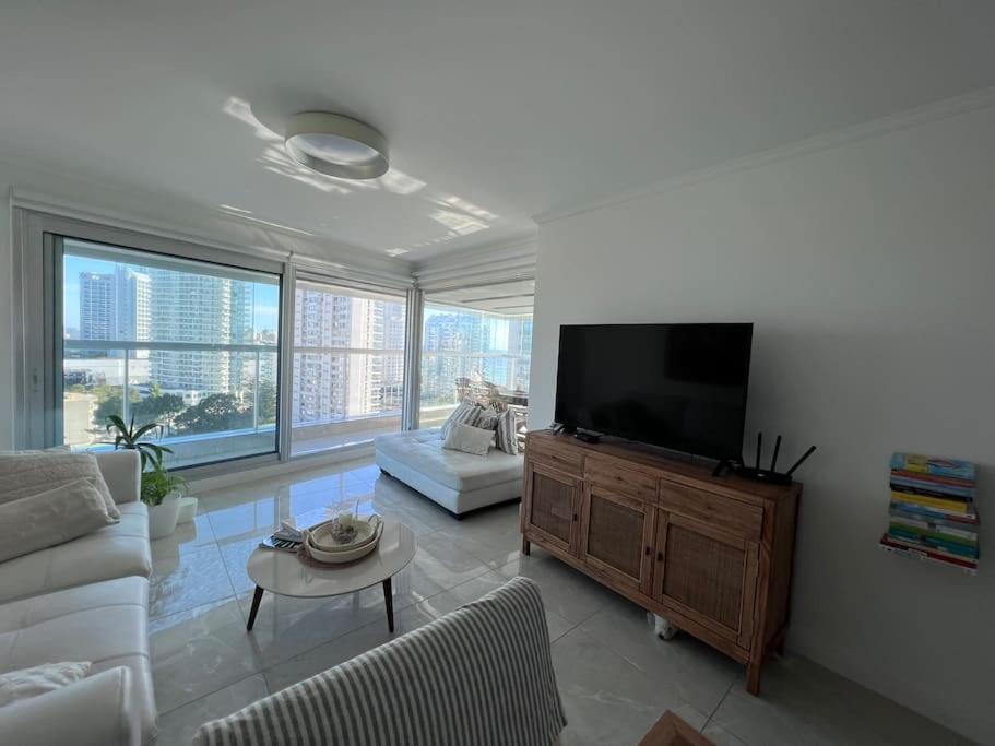 uma sala de estar com um sofá branco e uma televisão de ecrã plano em Miami Boulevard II excelente, a 100 metros del mar em Punta del Este