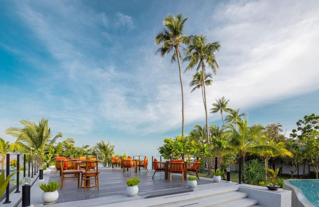 a deck with tables and chairs and palm trees at The Culture Samui in Bangrak Beach