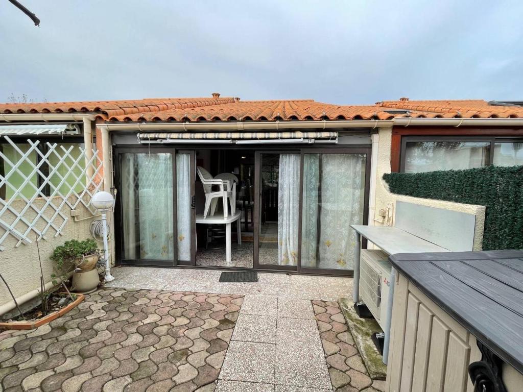 une maison avec une terrasse dotée d'une chaise blanche dans l'établissement Maison 2 pièces/mezzanine climatisée, 6 couchages, proche mer avec terrasse et parking privé - FR-1-225D-161, à Saint-Cyprien