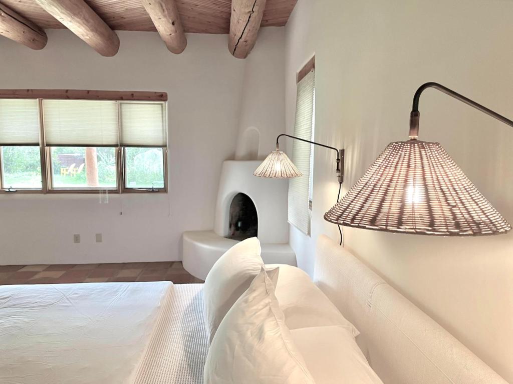 1 dormitorio con 2 lámparas, 1 cama y chimenea en Hacienda Del Sol, en Taos
