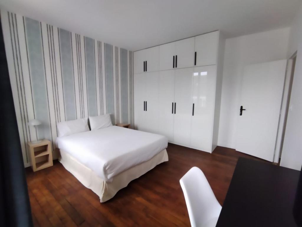 a bedroom with a white bed and a table and chairs at Smart Inn Melun Centre- Appartement 2 chambres in Melun