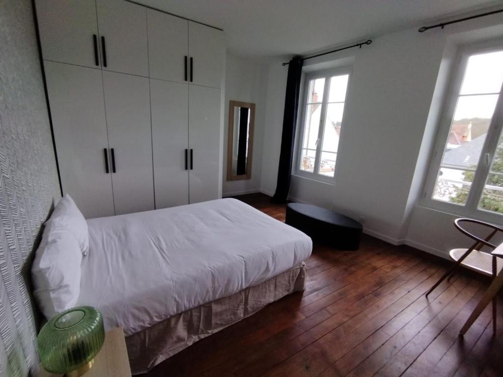 a bedroom with a white bed and two windows at Smart Inn Melun Centre- Appartement 2 chambres in Melun