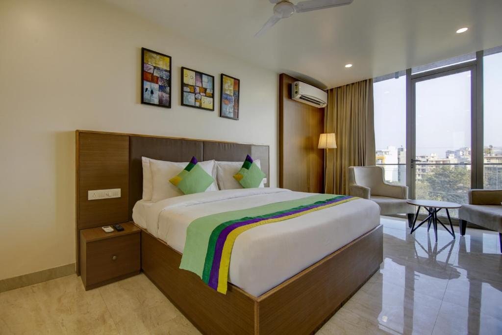 a bedroom with a large bed and a living room at Treebo Trend Grand Gurugram in Gurgaon