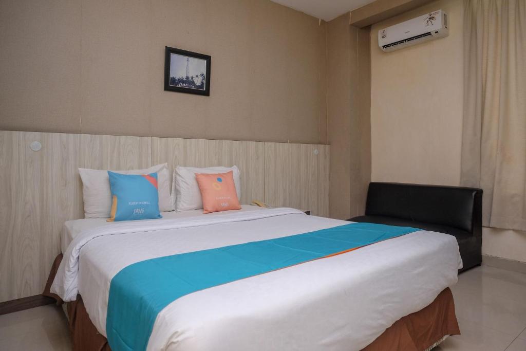 a bedroom with a large bed with colorful pillows at Sans Hotel Lynt Makassar in Makassar