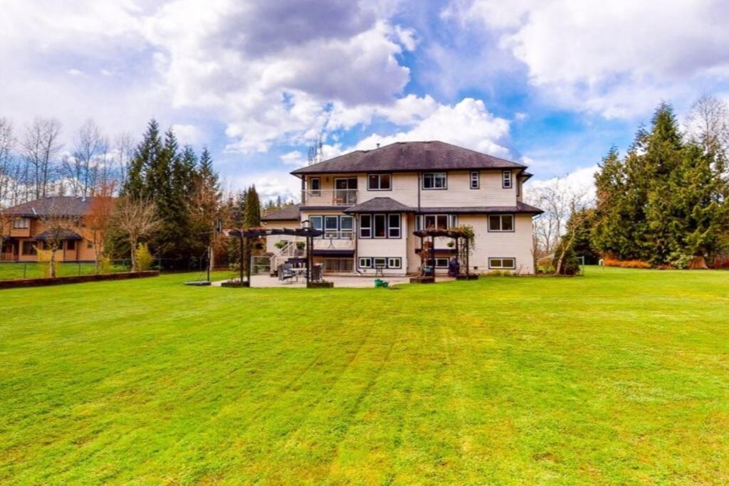 ein großes Haus mit einem großen Grasfeld in der Unterkunft Beautiful 3-bedroom Suite on 1 Acre in Maple Ridge District Municipality