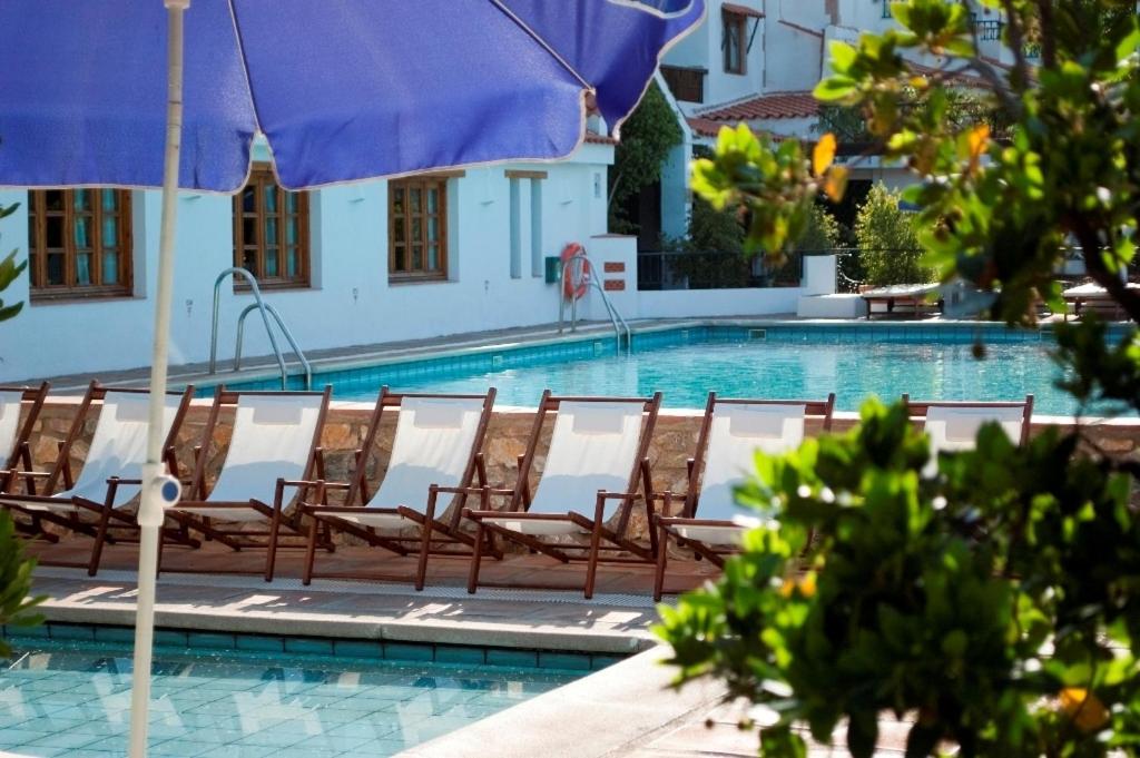 a swimming pool with chairs and an umbrella at Hotel Alcadima in Lanjarón